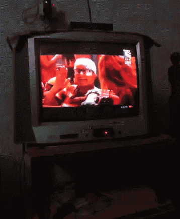 a tv shows a man in glasses and a hat on the screen