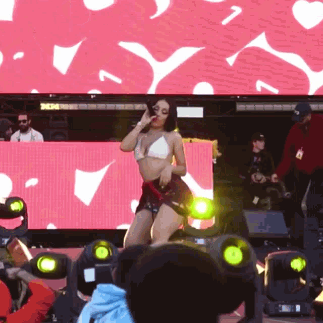 a woman in a bikini is dancing on a stage in front of a large screen that says 3k34