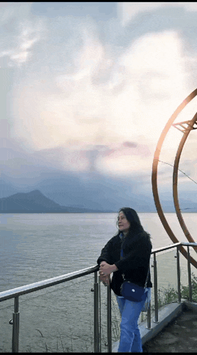 a woman is leaning on a railing overlooking a body of water