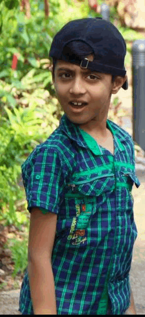 a young boy wearing a plaid shirt and a black baseball cap