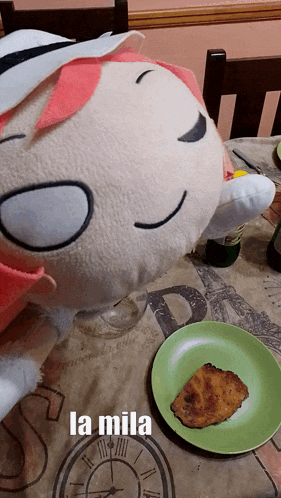 a stuffed animal is laying on a table next to a plate of food and the word la mila