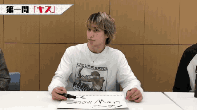 a man sitting at a table with a sign that says snow man on it