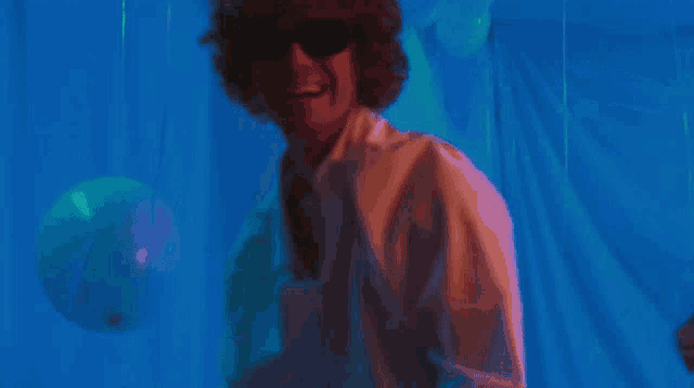 a man with curly hair is playing a guitar in a dark room