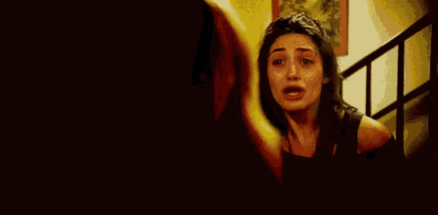 a woman is crying while standing on a set of stairs with a man holding her hand .