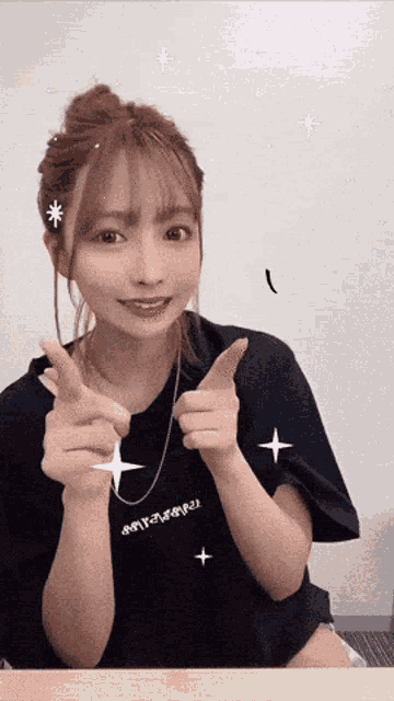 a young woman is giving a thumbs up sign while wearing a black shirt .