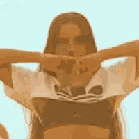 a woman in a crop top and shorts is making a heart with her hands .