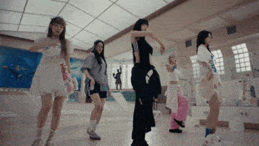 a group of women are dancing in a room with a statue in the background