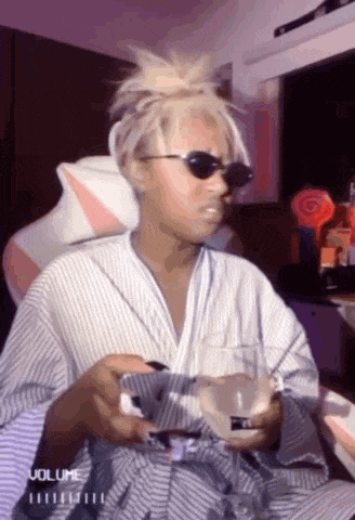 a woman wearing sunglasses and a robe is holding a glass of wine and a cell phone .