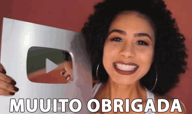 a woman holding a sign that says muuito obrigada