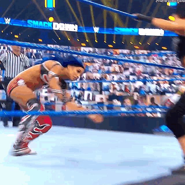 a woman in a wrestling ring with a sign that says smack down in the background