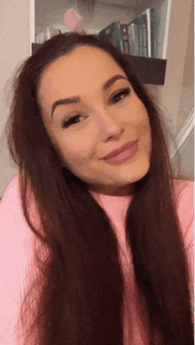 a woman wearing a pink sweater looks at the camera