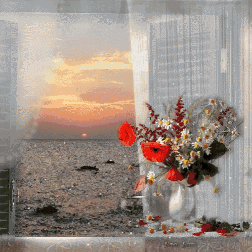 a vase of flowers sits in front of a window overlooking the ocean at sunset
