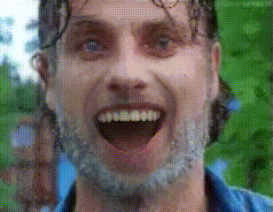 a man with a beard is smiling with his mouth open and his eyes closed .