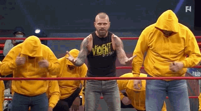a man in a yellow hoodie is standing in a wrestling ring