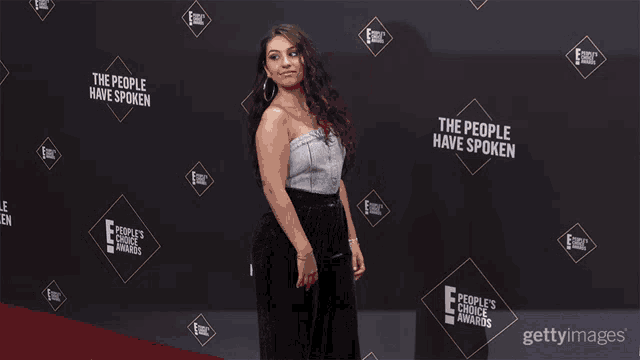 a woman stands on a red carpet with the words the people have spoken behind her