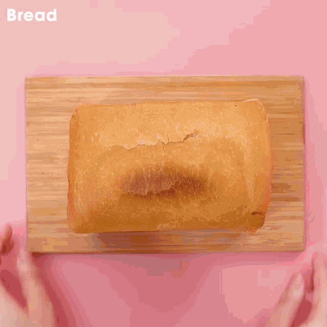 a person cutting a loaf of bread with a knife on a cutting board