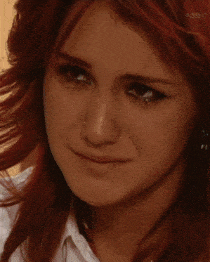 a close up of a woman 's face with red hair .