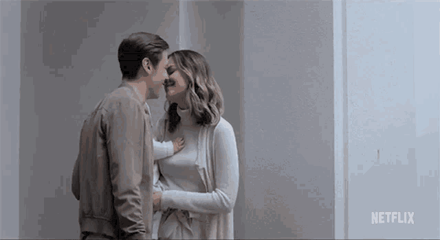 a man and a woman are kissing while holding a baby in a room .