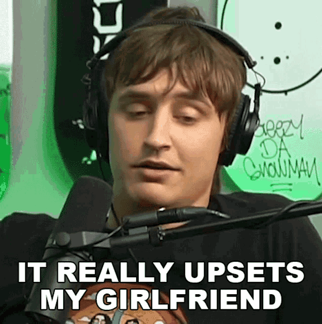 a man wearing headphones is talking into a microphone and says it really upsets my girlfriend .