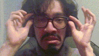 a man with glasses and a beard is adjusting his glasses with his hands