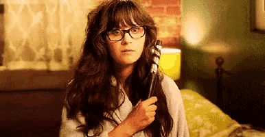 a woman with glasses is holding a curling iron in her hand .