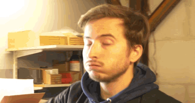 a man wearing a blue hoodie is making a face