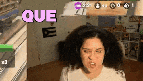 a woman wearing headphones is playing a video game and says que