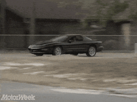a black car is driving down a road with motorweek written on the bottom of the screen