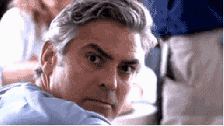 a man with gray hair is looking over his shoulder at the camera