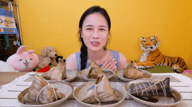 a woman is sitting at a table with plates of food and a stuffed tiger in the background .