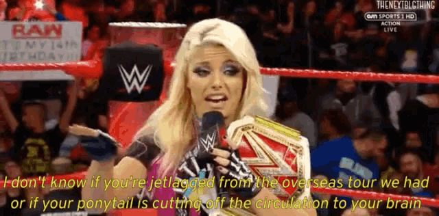 a woman in a wrestling ring is talking into a microphone while holding a championship belt