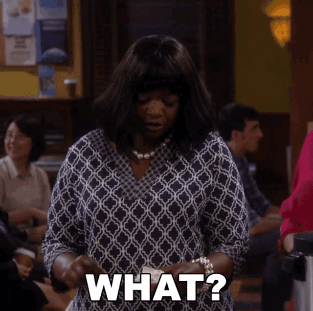 a woman in a plaid shirt says what in front of a group of people