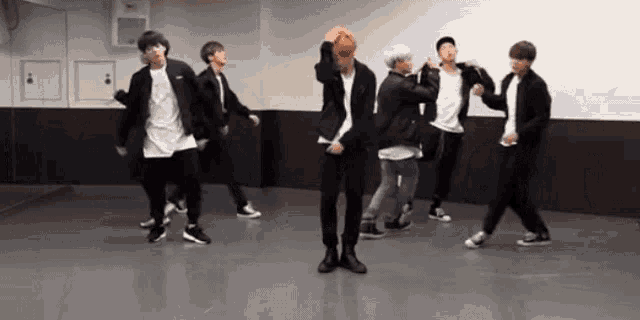 a group of young men are dancing in front of a mirror