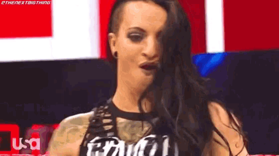 a woman with long black hair is making a funny face while standing in front of a red and white wall .
