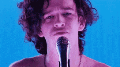 a close up of a man singing into a microphone .