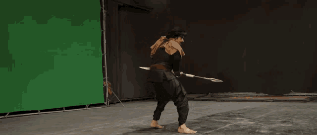 a person is holding a sword in front of a green screen