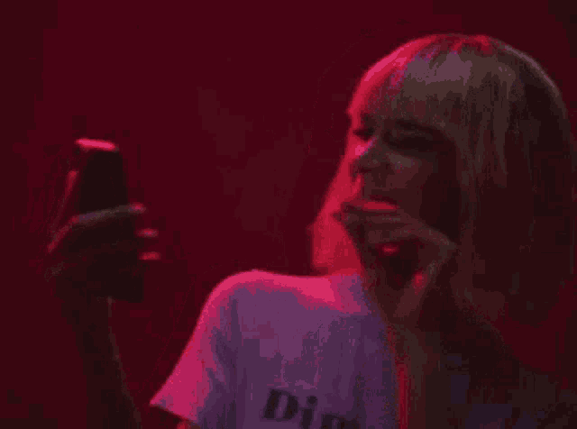 a woman is taking a selfie with her phone in a dark room .