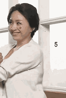 a woman with a red spot on her face is standing in front of a window with the number 5 on it .