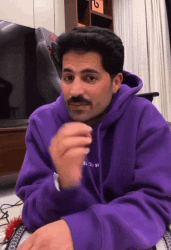 a man with a mustache is wearing a purple sweatshirt