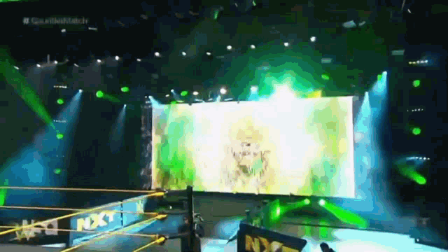 a wrestling ring with a large screen and a sign that says nxt