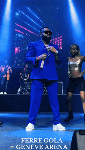 a poster for ferre gola geneve arena shows a man in a blue suit on stage