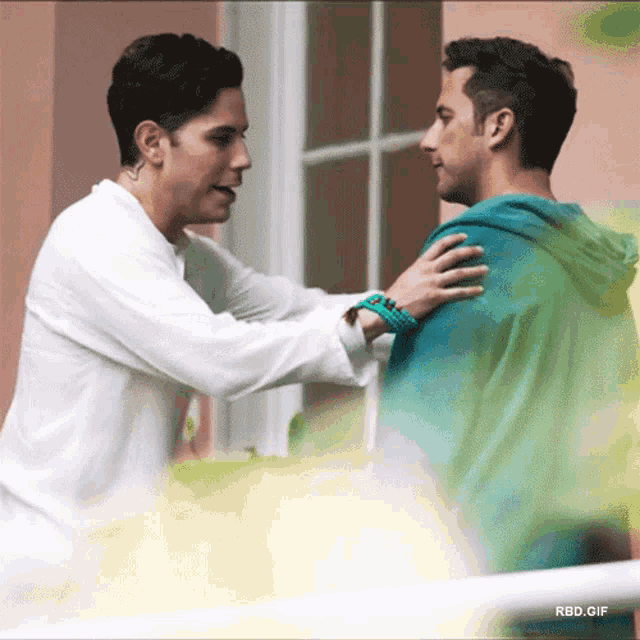 a man in a white shirt is hugging another man in a green hoodie