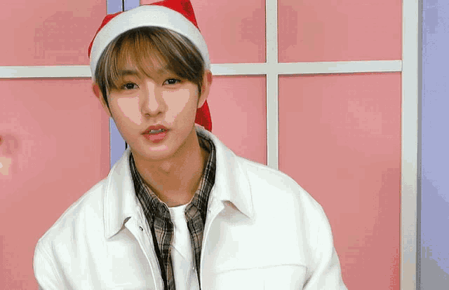 the boy is wearing a santa hat and a white jacket .
