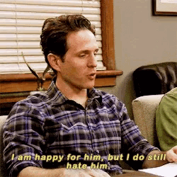 a man in a plaid shirt is saying i am happy for him but i do still hate him