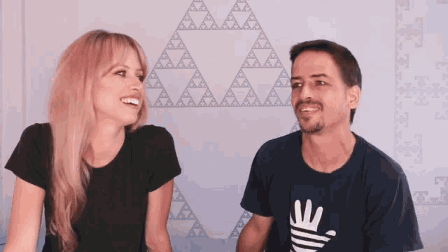 a man and a woman are sitting next to each other and the man is wearing a shirt with the letter e on it