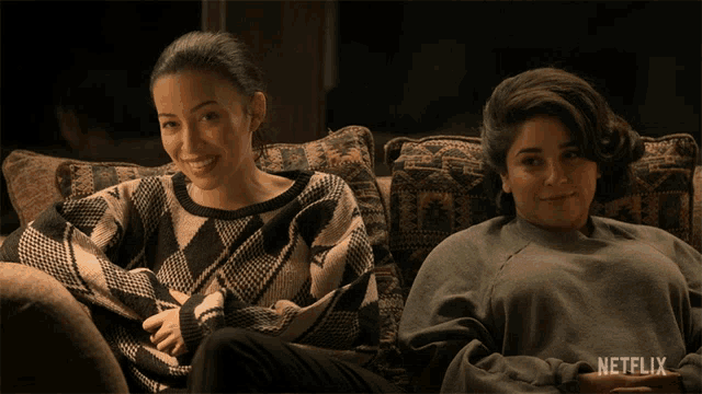 two women are sitting on a couch with a netflix logo in the background