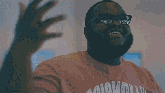 a man with glasses and a beard is smiling and wearing a shirt that says ' los angeles ' on it