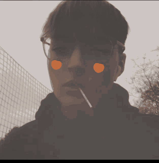 a young man wearing glasses and ear buds is smoking a cigarette with peach faces drawn on his face