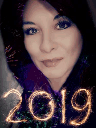 a woman 's face is surrounded by fireworks and the year 2019 is written in sparklers