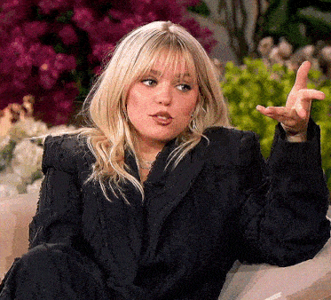 a woman in a black jacket is sitting on a couch